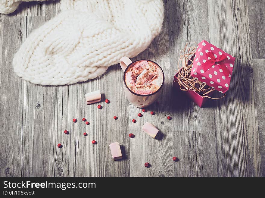 Overhead view of coffee with marshmallows, open gift box and white fabric on wooden background. Overhead view of coffee with marshmallows, open gift box and white fabric on wooden background.