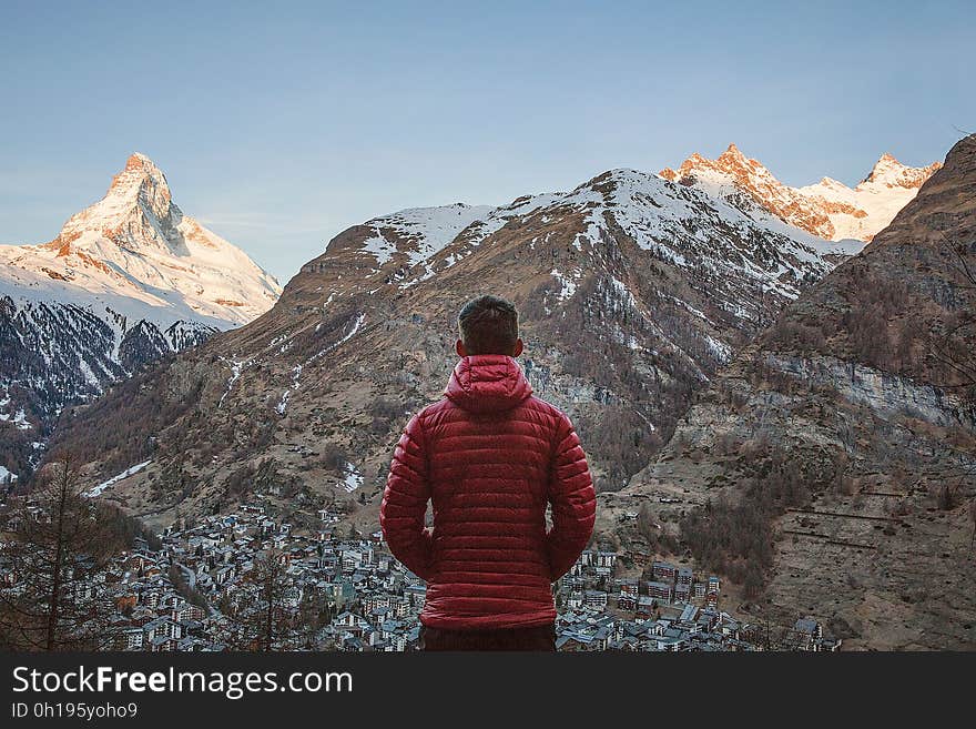 A traveler looking over a valley and a mountain peak. A traveler looking over a valley and a mountain peak.