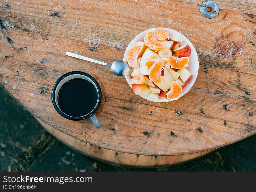 A cup of coffee with a bowl of fruit salad on a cable drum. A cup of coffee with a bowl of fruit salad on a cable drum.