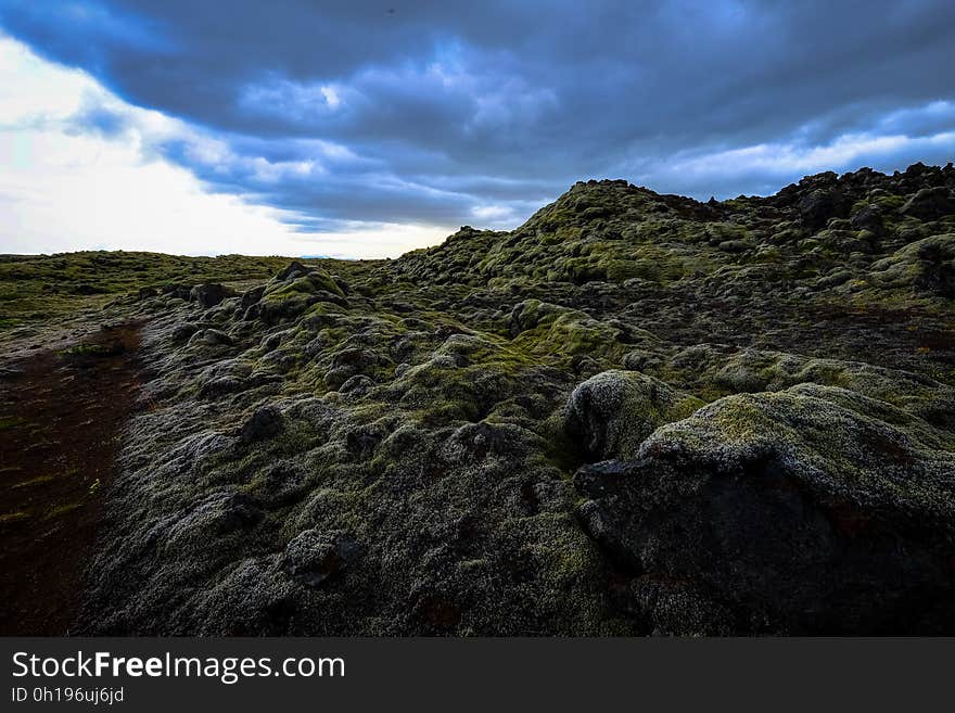 A landscape with green hills and mossy rocks.