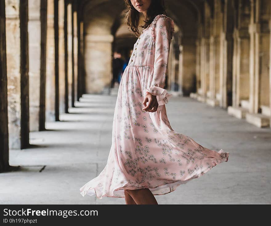 A woman in pink dress in a corridor.