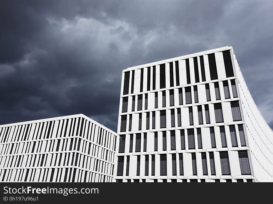 A pair of white buildings against the clouds.