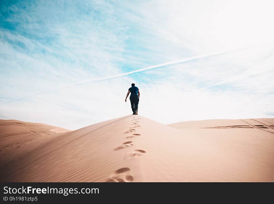 A man walking on a sand dune. A man walking on a sand dune.