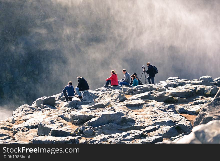 A group of people on a rocky mountain ledge. A group of people on a rocky mountain ledge.