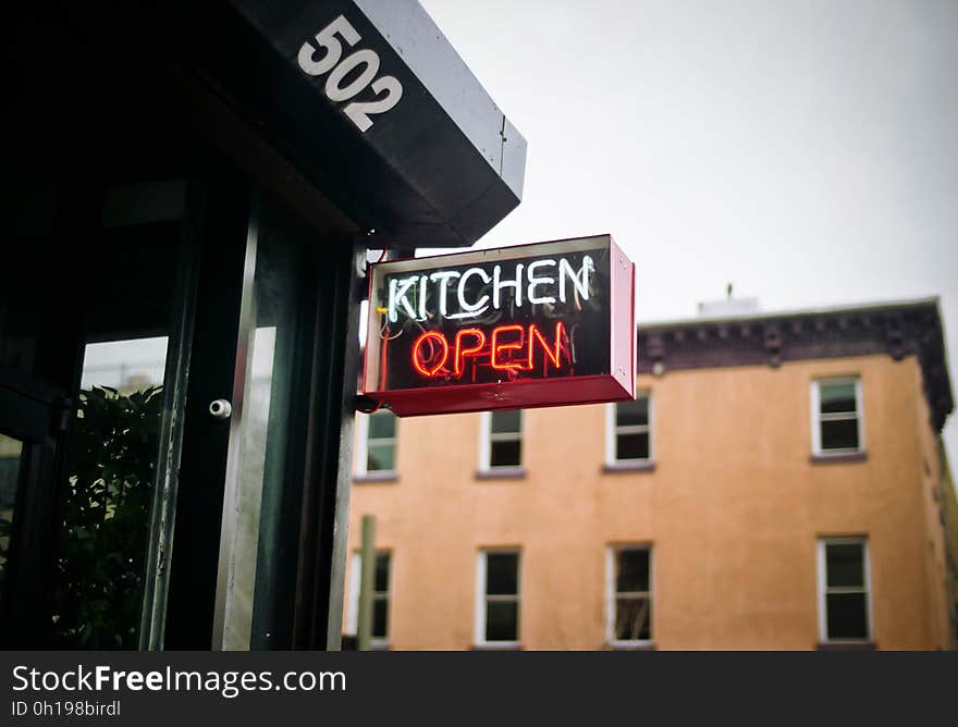 A neon kitchen open sign at the restaurant entrance.