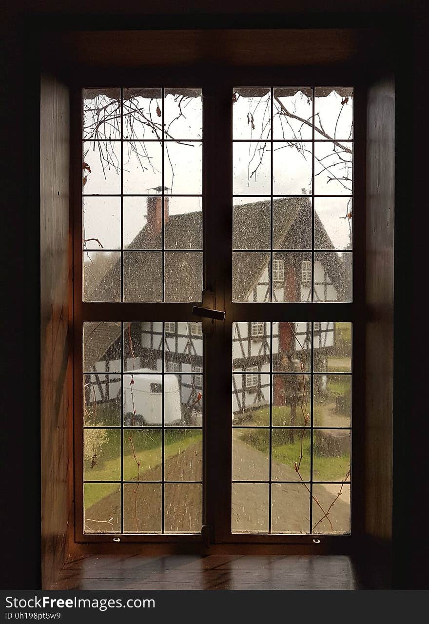 A classic window panel with a view of an old half-timbered house.