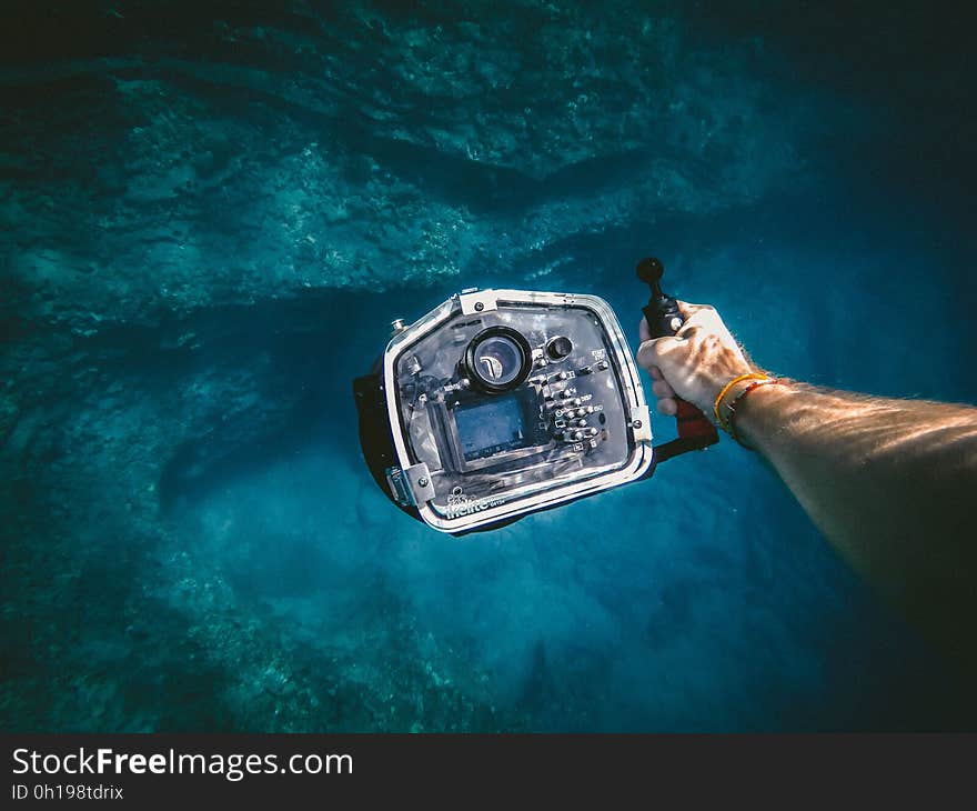 A diver with a camera diving in an underwater cave.