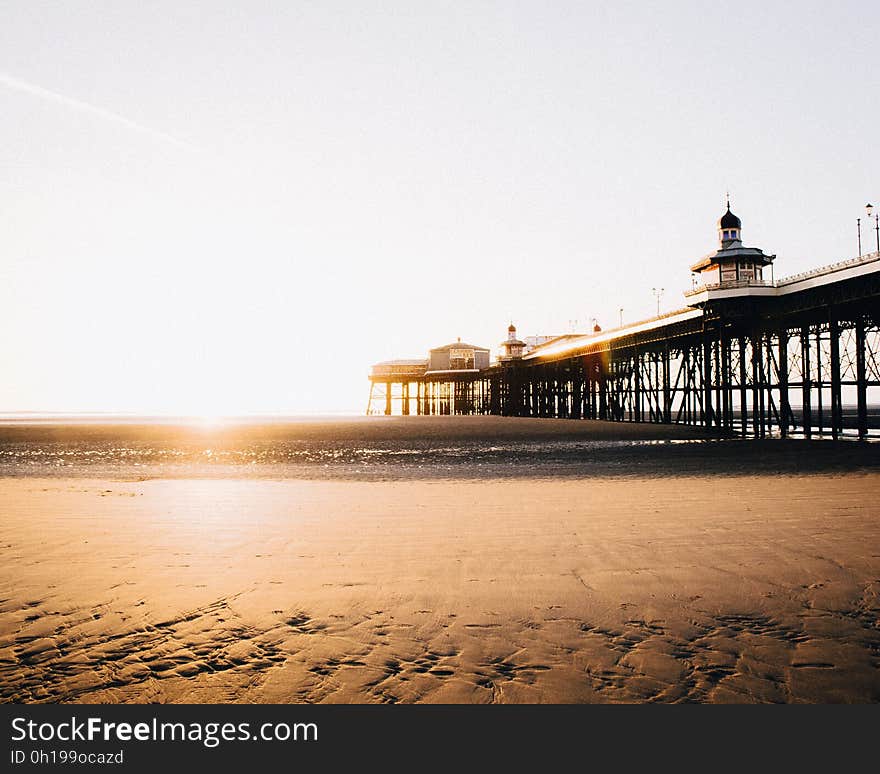 Scenic view of beach and pier at sunset.