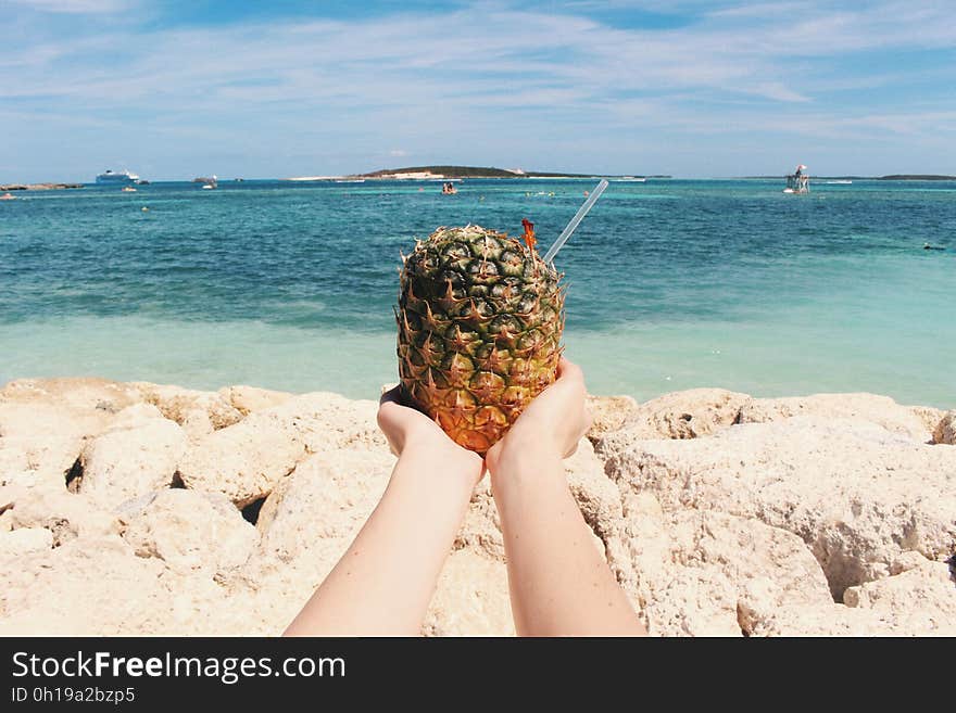 A person holding a tropical drink on a beach. A person holding a tropical drink on a beach.