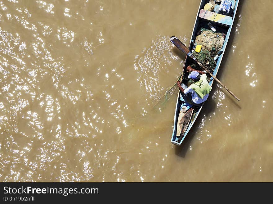 Top view of a fisherman in a boat pulling the net out of the water. Top view of a fisherman in a boat pulling the net out of the water.