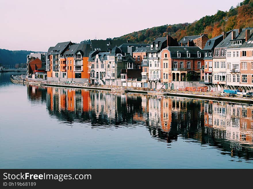 Colorful waterfront buildings, homes, hotels and apartments, some old and some in modern architectural style, with reflections in the river.