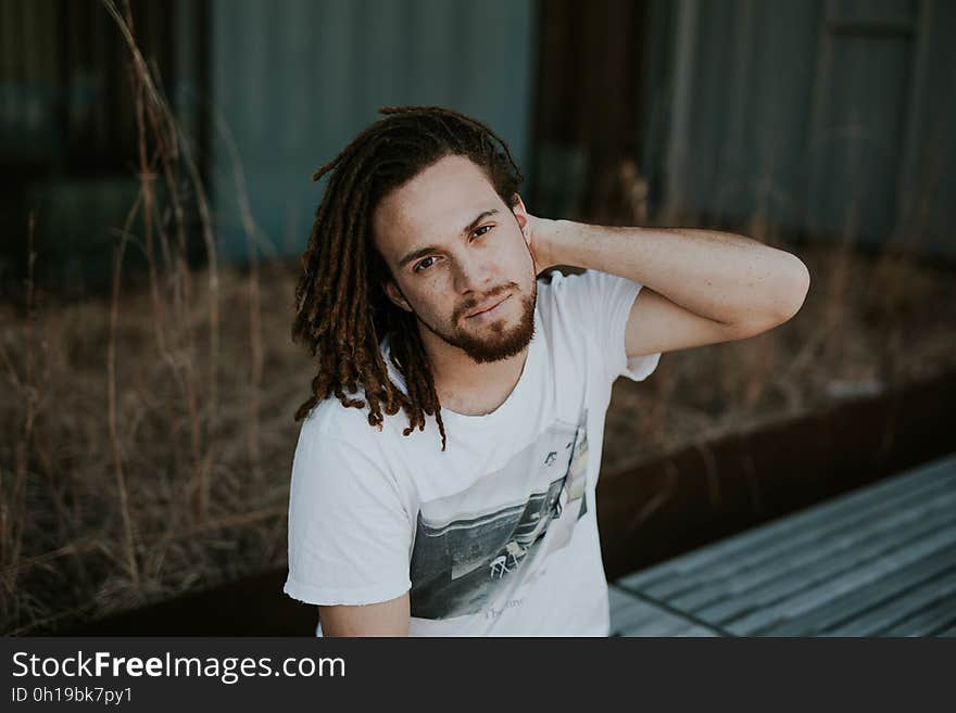 Portrait of man with cornrow braids sitting outdoors on sunny day. Portrait of man with cornrow braids sitting outdoors on sunny day.