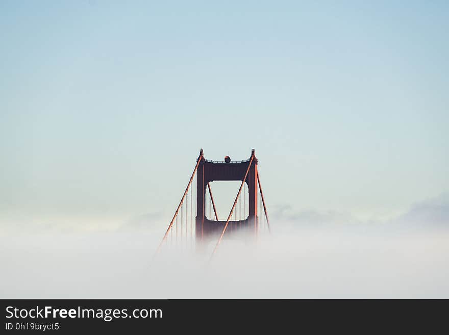 The top of a pylon of the Golden Gate bridge peeking out from the mist. The top of a pylon of the Golden Gate bridge peeking out from the mist.