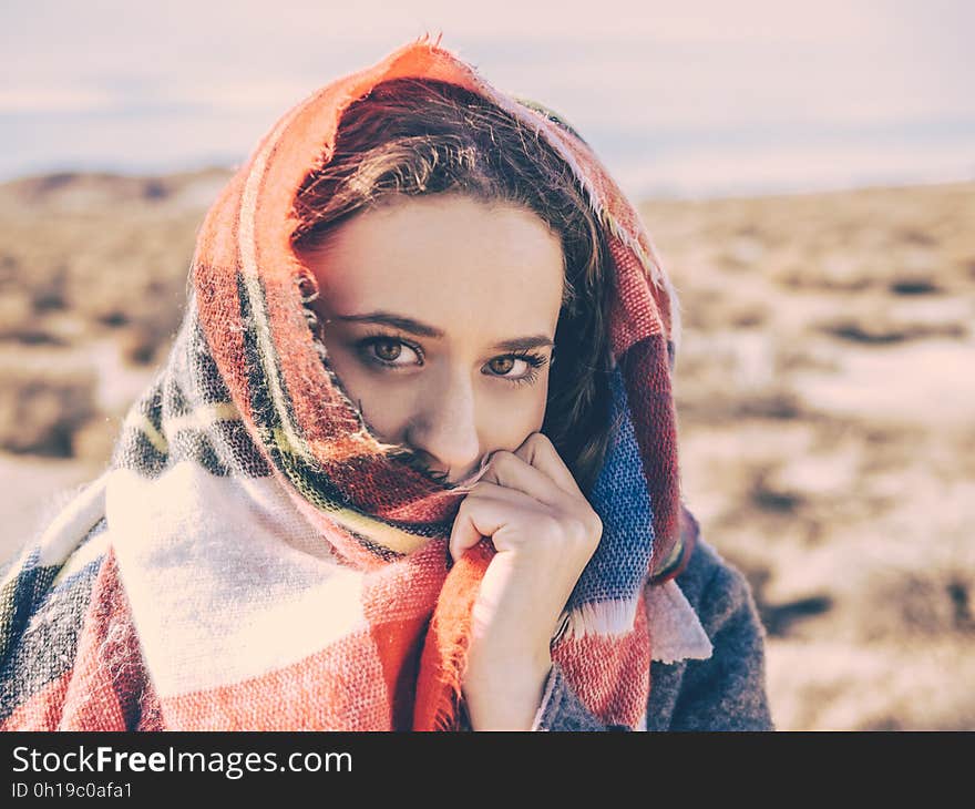 A portrait of a young woman with a plaid scarf over her face. A portrait of a young woman with a plaid scarf over her face.