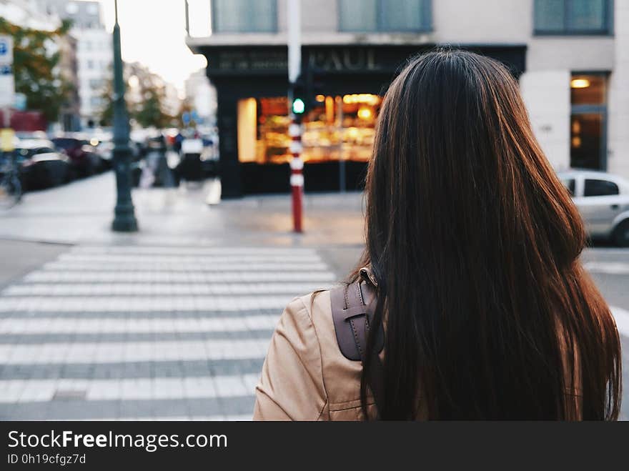 Girl with umbrella standing at a zebra crossing about to cross the road to reach a bakery shop. Girl with umbrella standing at a zebra crossing about to cross the road to reach a bakery shop.