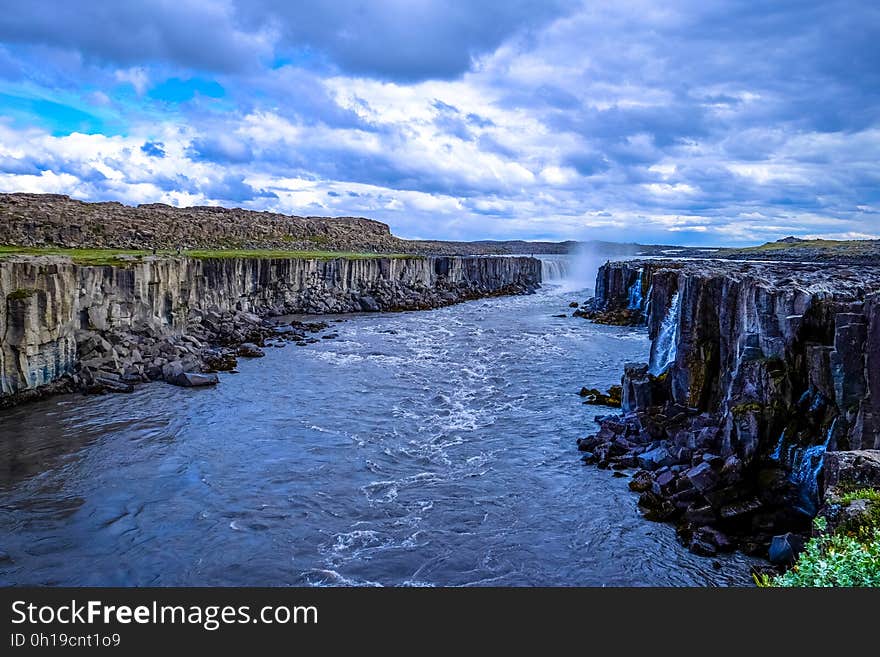 A river flowing through a canyon and waterfall in the distance. A river flowing through a canyon and waterfall in the distance.