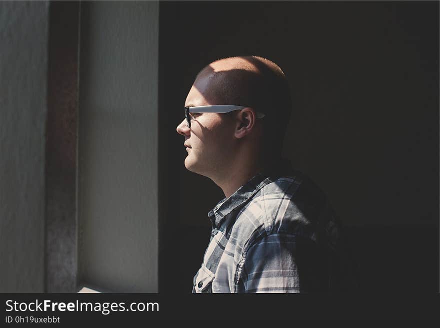 Man Standing Looking Straight Forward Through the Window