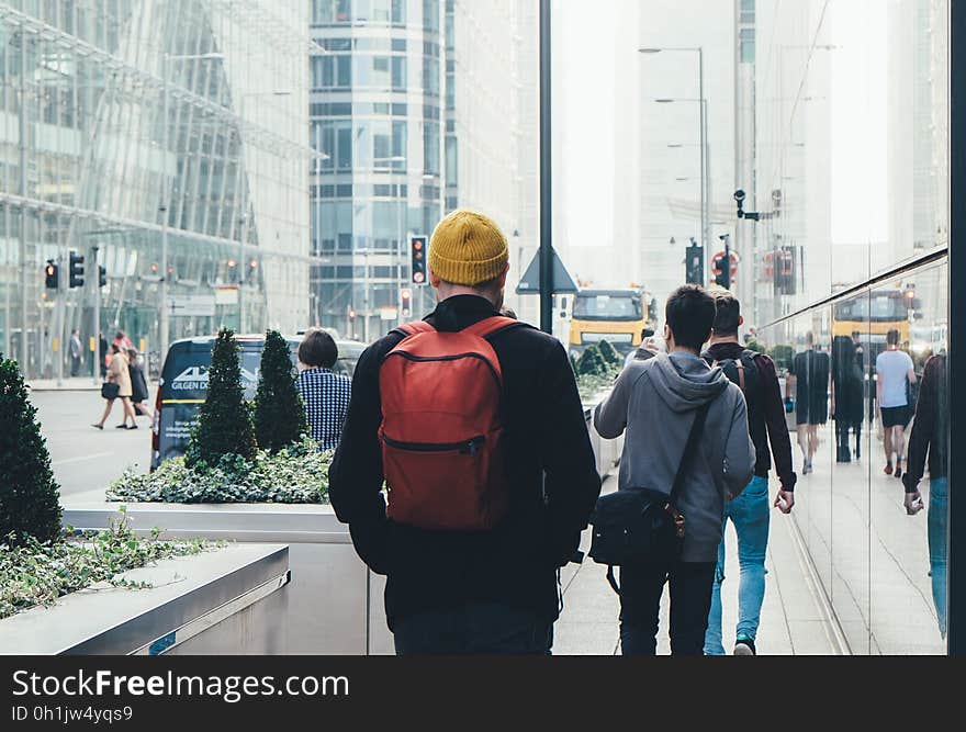 Man in Black Jacket and Carrying Red Backpack