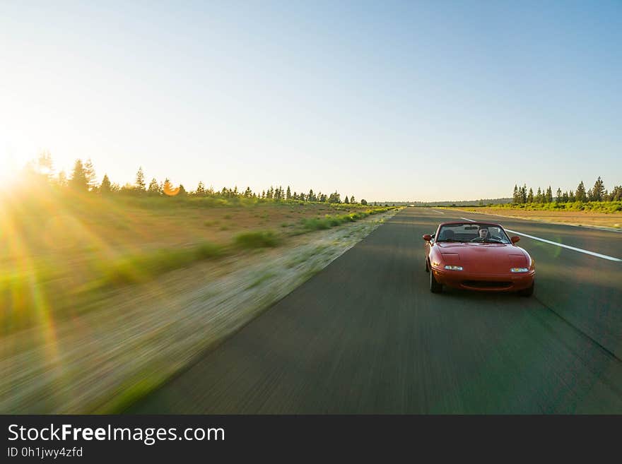 Red Sports Car Running on the Road Under Blue Sky during Daytime