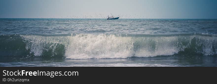 Black Ship on Green Sea Under White and Blue Sky at Daytime