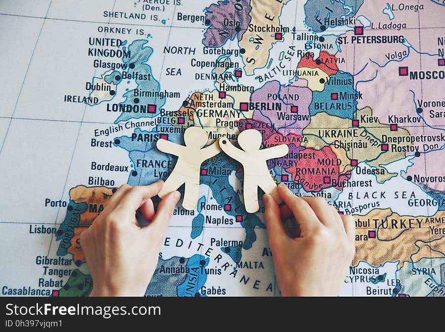 Hands holding wooden little men on map background. Symbol of friendship, partnership or cooperation between countries