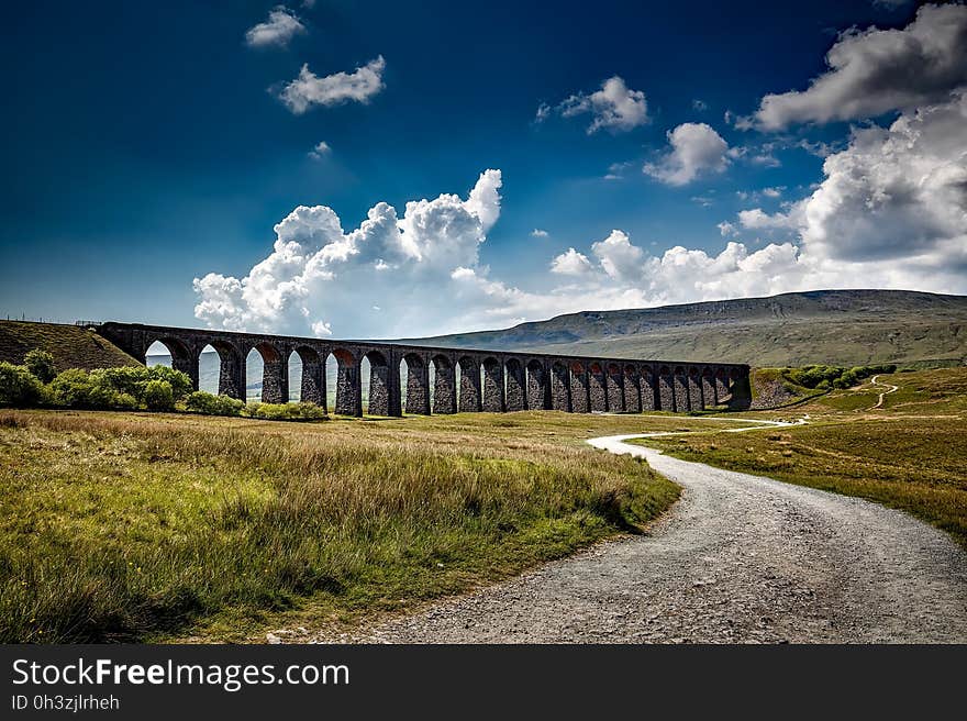 Brown Bridge on Green Grass Field Near Mountain