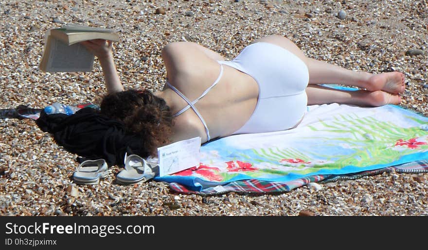 woman reading book on beach