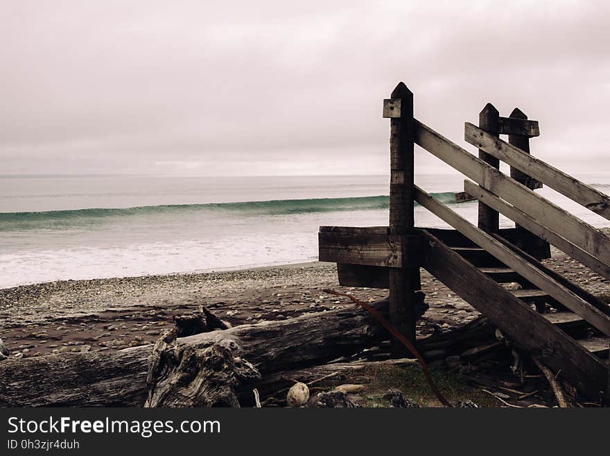 Brown Wooden Stair Near Seashore Under Dark Sy