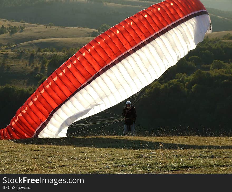 Man on the Ground With a Red Black and White Parachute