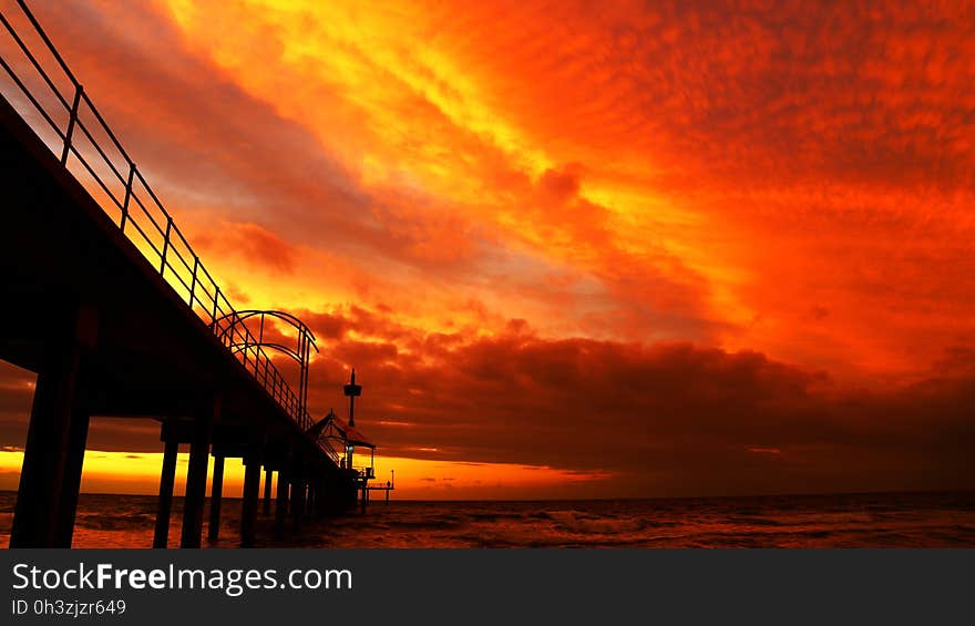 Black Bridge Under Orange Sky during Sunset