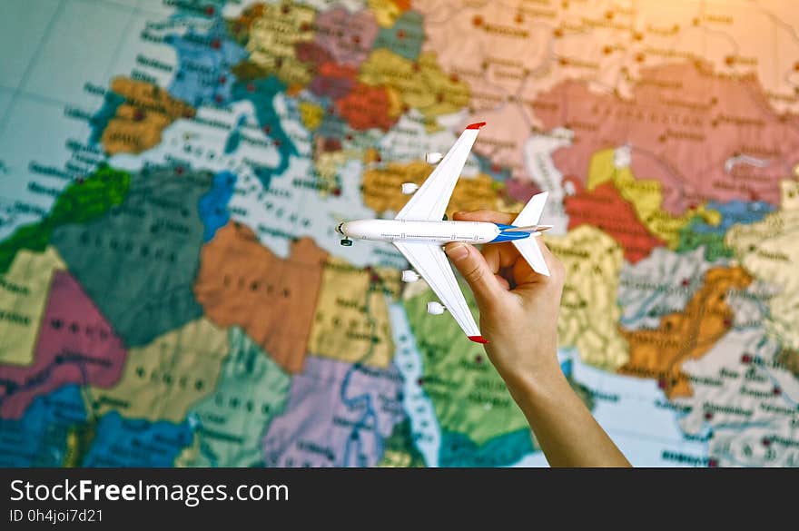 Hand with toy model of airplane on map