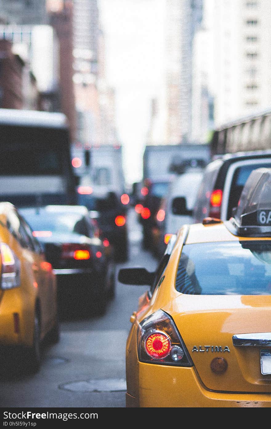 Yellow Altima Taxi Surrounded by Vehicles during Daytime