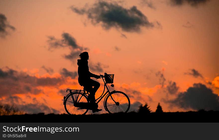 Silhouette of Person Riding a Bike during Sunset