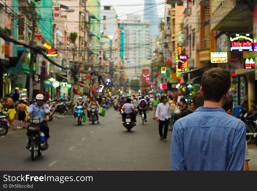 Man in Blue Shirt Standing Near Stores during Daytime