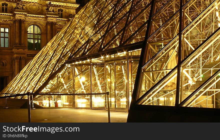 Metal Frame Glass Pyramid Outside a Museum With Yellow Lights during Nighttime