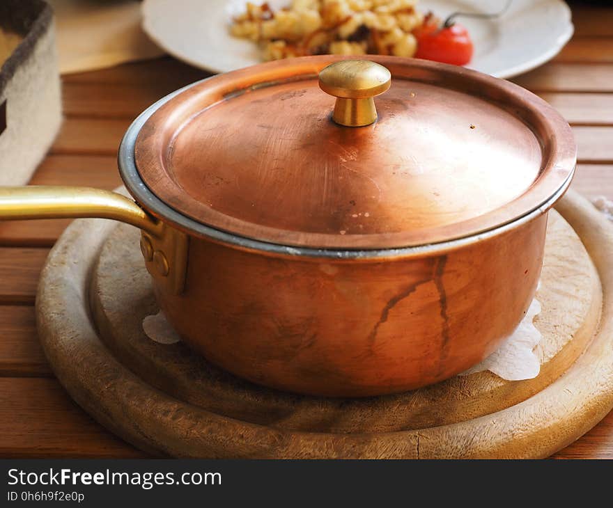 Brown Lidded Cooking Pot on Gray Round Wooden Coaster