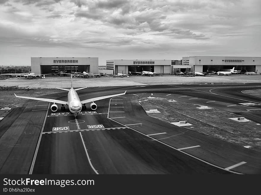 Gray Scale of Air Plane on Runway Under Cloudy Day