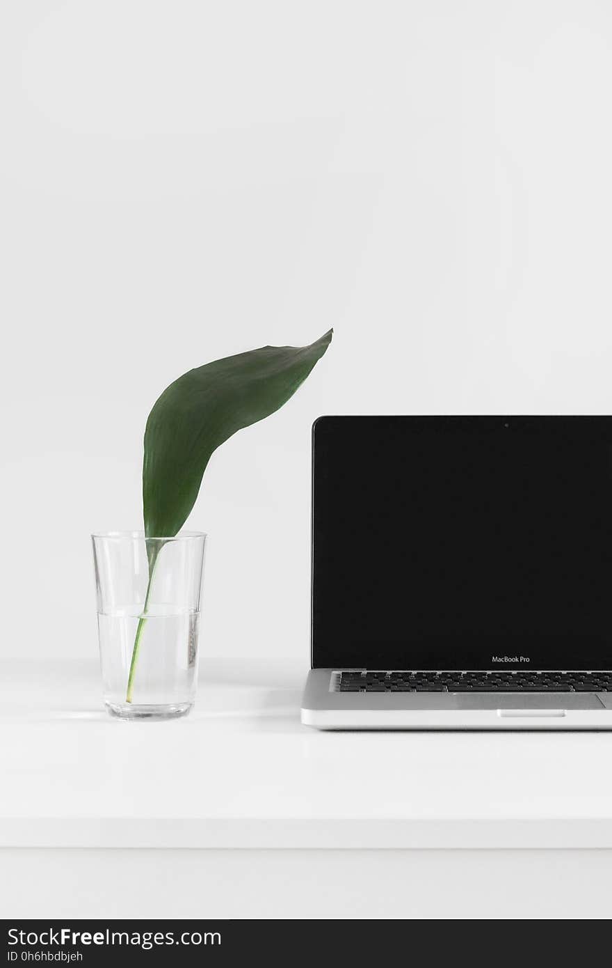 Clear Drinking Glass Near Macbook Pro