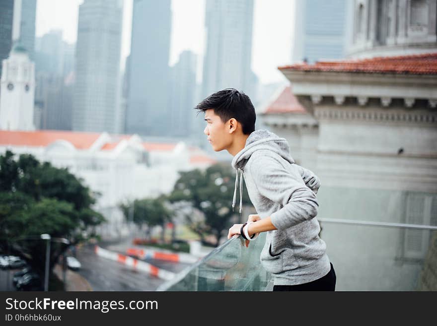 Man Wearing Grey Pullover Jacket on a Building in the City during Dayitme