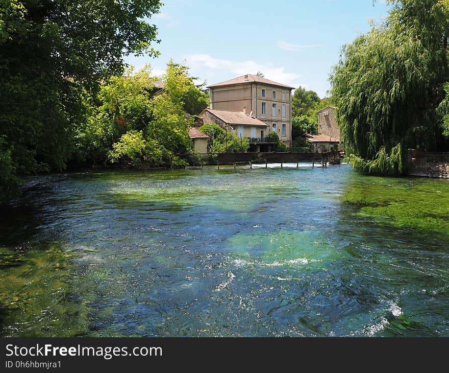 Brown Cement House Beside River Surrounded by Trees during Daytime