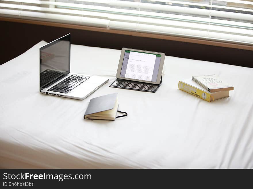 Macbook Pro over White Fabric Sheet Beside White Ipad