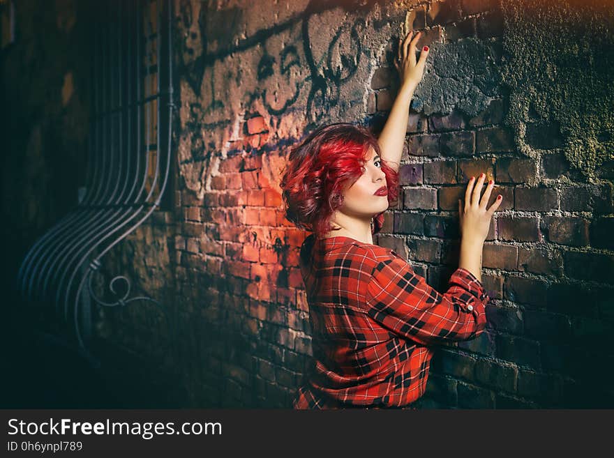 Woman in Red Black and White Plaid Holding Gray Concrete Wall