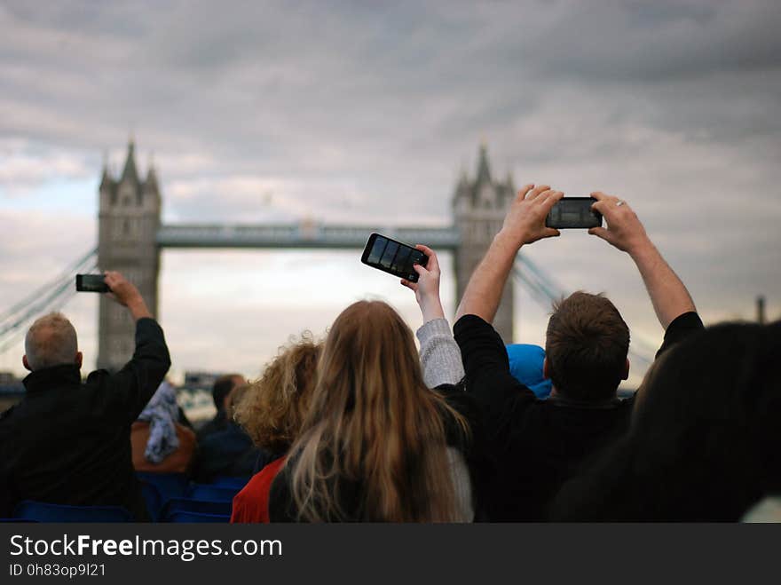 People Taking Picture at Tower Bridge Under Gray Clouds