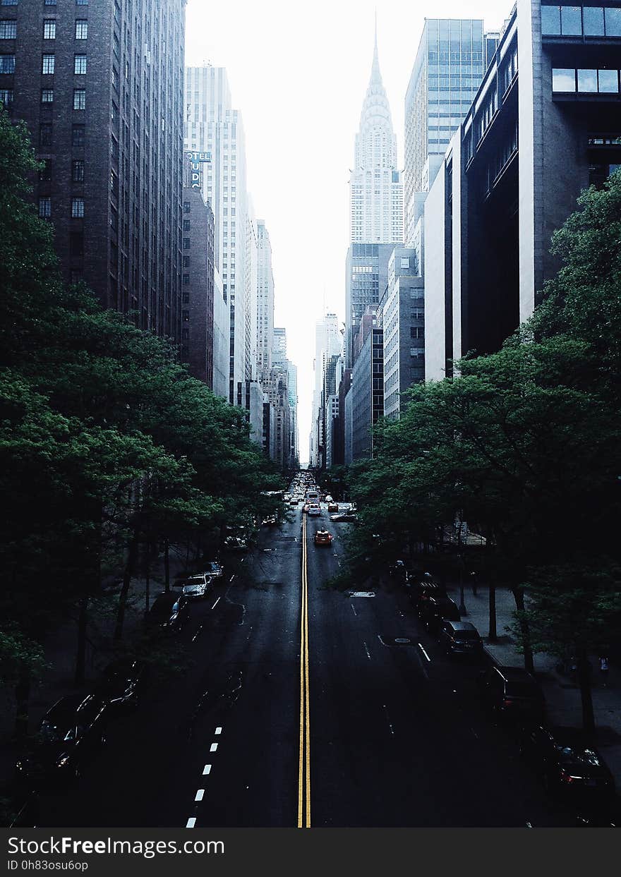 White and Red Car on Black Concrete Narrow Road in Between High Rise Buildings Photograph