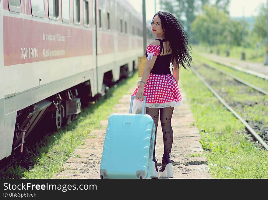 Young Woman With Luggage Standing on Train in City