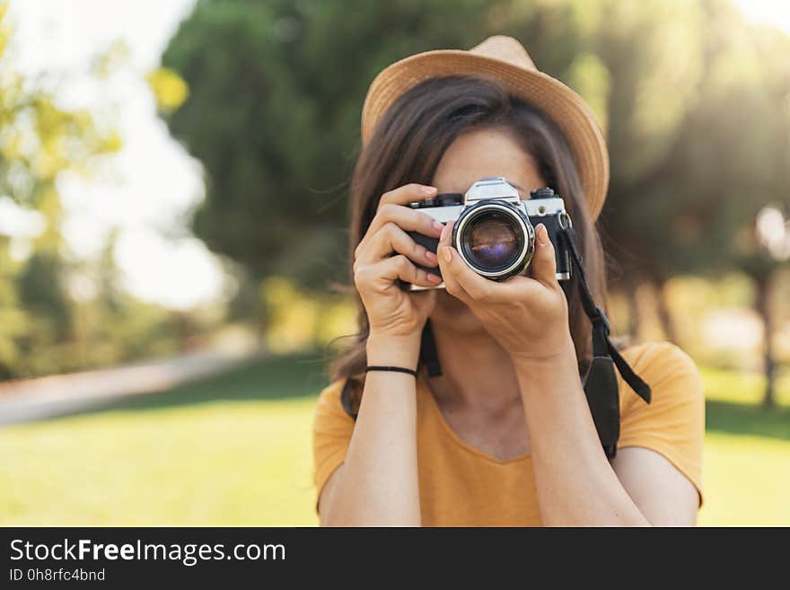 Young woman using a camera to take photo at the park. Young woman using a camera to take photo at the park.