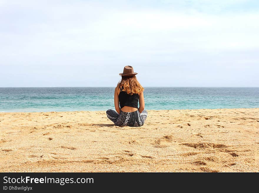 Woman Sitting on Seashore at Daytime