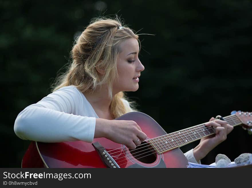 Woman&#x27;s Playing Red and Black Wooden Acoustic Guitar