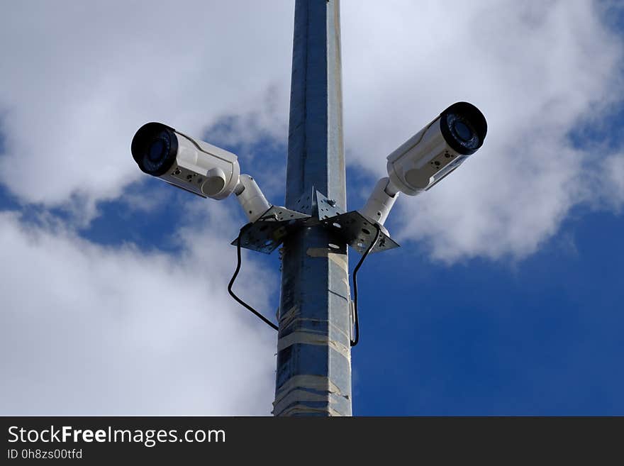 Two surveillance cameras on the same support on the street under the sky. Two surveillance cameras on the same support on the street under the sky