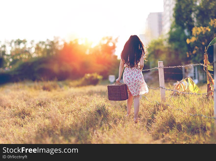 Woman in Brown Floral Dress Walking Near Fence